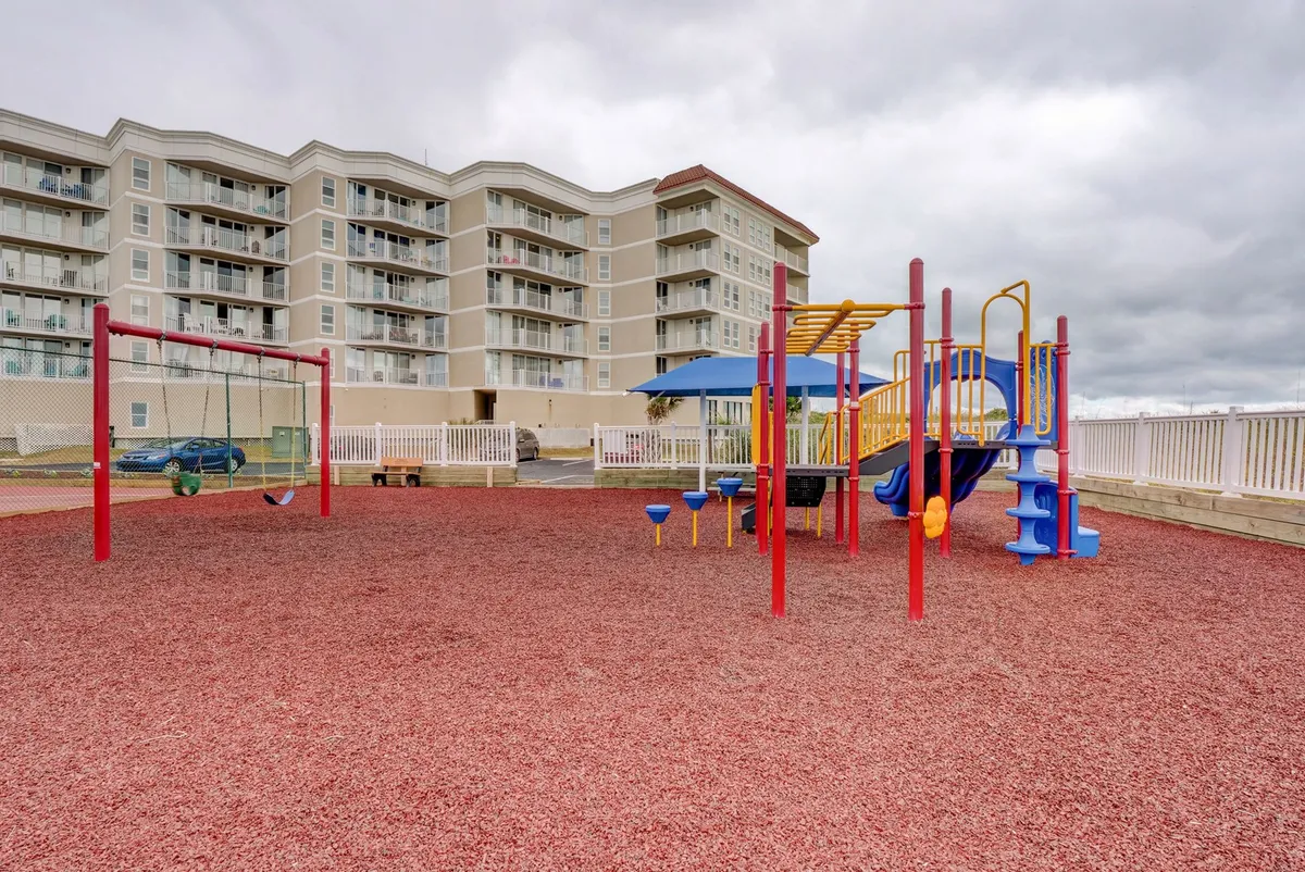 A bright, colorful playground featuring swings and modern play structures, surrounded by open space perfect for running, games, and family picnics. Children are pictured smiling and playing, evoking a sense of joyful energy and community.