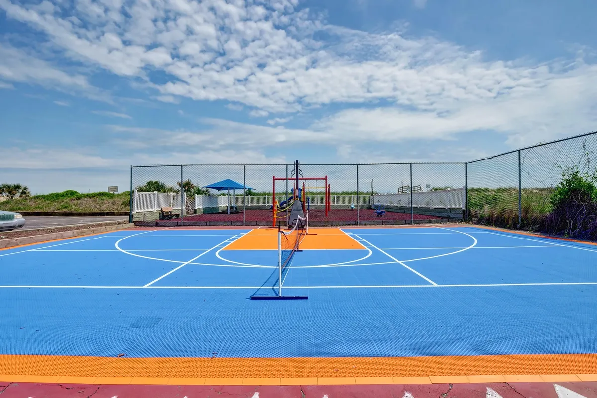 An energetic outdoor scene highlighting a colorful sports court with a basketball hoop, tennis net, and surrounding greenery. The vibrant setting encourages physical activity and outdoor recreation, providing a glimpse of facilities ideal for wellness and active breaks.