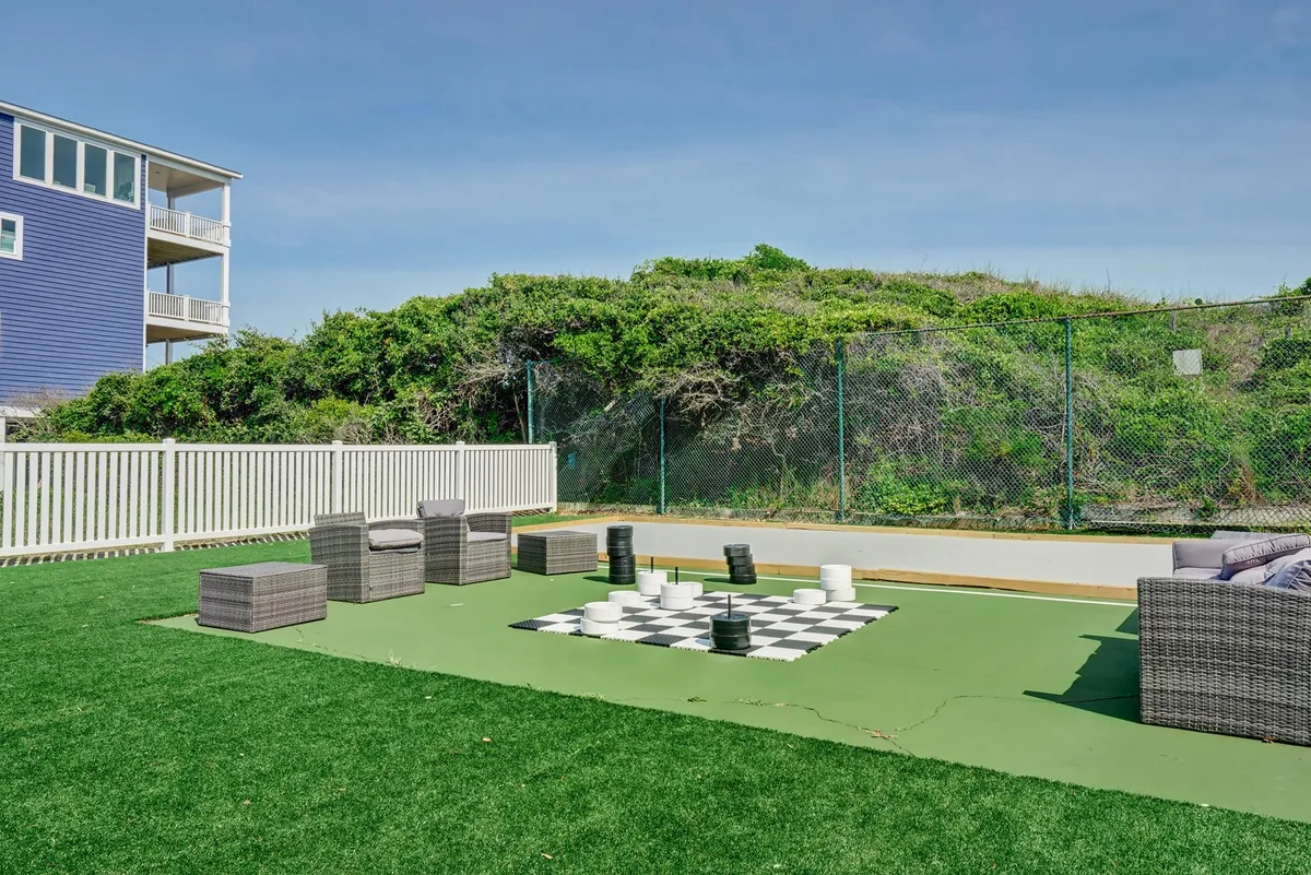 An outdoor chess set is the focal point of this playful scene, with a seating area and green grass inviting relaxation and socializing. The space is designed for both strategic games and leisurely outdoor gatherings, ideal for families looking to connect in a fun, casual environment.